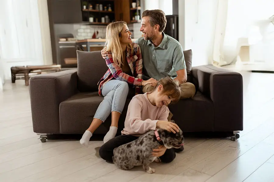 Happy family with a child and dog inside their living room, enjoying life after securing a dhoas loan.