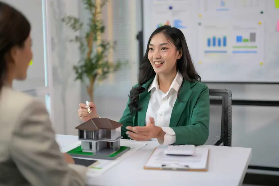 Defence mortgage borker presenting a house model to a client, highlighting housing options that could be financed with defence loans